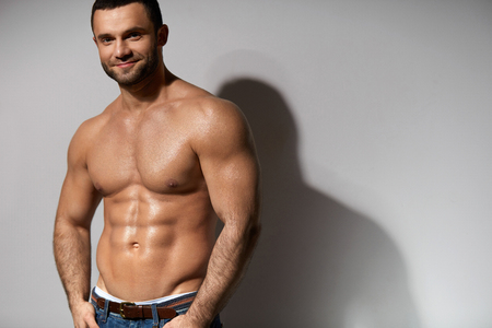 Male Fitness Model With Sexy Muscular Body Portrait. Handsome Hot Young Man With Fit Athletic Body Shape, Perfect Abs Muscles And Naked Torso On Grey Background. Bodybuilding Concept. High Resolutionの写真素材
