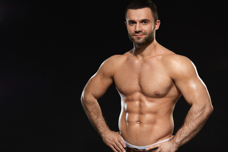 Muscular Male Body. Closeup Of Handsome Healthy Young Man With Perfect Trained Naked Torso. Portrait Of Sexy Male With Fit Abs And Biceps On Black Background. Bodybuilding Concept. High Resolutionの写真素材