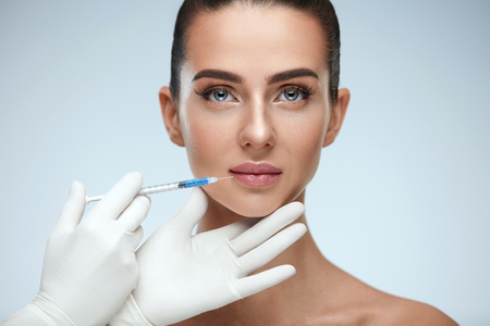 Beauty Injection. Closeup Of Doctor Hands With Syringe Near Female Face. Portrait Of Beautiful Woman With Soft Skin, Perfect Makeup Receiving Facial Skin Lifting Treatment, Injections. High Resolutionの写真素材