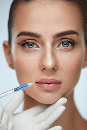 Plastic Surgery. Closeup Of Doctor Hands Doing Beauty Hyaluronic Lip Injection For Sexy Girl Lips. Portrait Of Beautiful Young Woman Getting Cosmetic Treatment Indoors. Skin Procedure. High Resolutionの写真素材