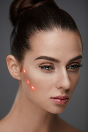 Beauty Treatment. Portrait Of Beautiful Young Woman With Soft Skin And Red Laser Points On Face. Closeup Of Sexy Healthy Woman Before Plastic Surgery On Grey Background. Cosmetology. High Resolutionの写真素材