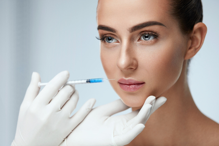 Beauty Injection. Closeup Of Doctor Hands With Syringe Near Female Face. Portrait Of Beautiful Woman With Soft Skin, Perfect Makeup Receiving Facial Skin Lifting Treatment, Injections. High Resolutionの写真素材
