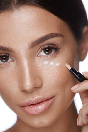 Skin Care. Portrait Of Beautiful Young Woman Face With Perfect Makeup And Healthy Smooth Skin. Closeup Of Female Applying Concealer On Skin Under Eyes, Doing Make-up. Beauty Cosmetics. High Resolutionの写真素材