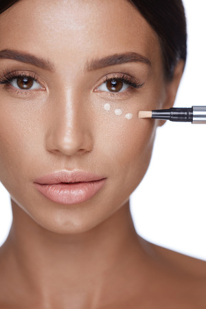 Skin Care. Portrait Of Beautiful Young Woman Face With Perfect Makeup And Healthy Smooth Skin. Closeup Of Female Applying Concealer On Skin Under Eyes, Doing Make-up. Beauty Cosmetics. High Resolutionの写真素材