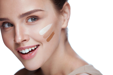 Beauty Cosmetics. Portrait Of Beautiful Young Woman With Tree Shades Of Skin Cream Tone On Face. Closeup Of Sexy Smiling Girl With Soft Smooth Skin And Natural Makeup. Foundation. High Resolutionの写真素材