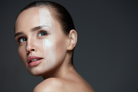 Skin Care. Closeup Of Beautiful Young Female Model With Pure Clean Skin And Natural Professional Makeup. Portrait Of Sexy Woman With Skin Tone Cream Mask Stripe On Face. Beauty Face. High Resolutionの写真素材