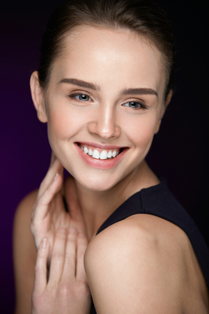 Woman Beauty Face. Closeup Beautiful Woman With Beauty Face Touching Her Soft Skin. Portrait Of Sexy Smiling Young Female Model With Fresh Professional Makeup And Perfect White Smile. High Resolutionの写真素材