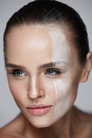 Skin Care Cosmetic Mask. Portrait Of Sexy Woman With Skin Tone Mask Cream Stripe Across Face. Closeup Of Beautiful Female With Soft Skin And Natural Makeup On Grey Background. High Resolutionの写真素材