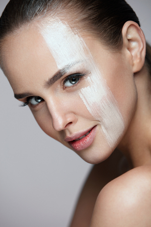 Skin Care Cosmetic Mask. Portrait Of Sexy Woman With Skin Tone Mask Cream Stripe Across Face. Closeup Of Beautiful Female With Soft Skin And Natural Makeup On Grey Background. High Resolutionの写真素材