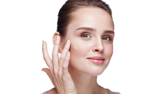 Beauty Face. Closeup Of Smiling Young Female Model With Smooth Soft Skin And Natural Facial Makeup. Portrait Of Beautiful Sexy Woman Putting Cream Foundation On Facial Skin. Cosmetics. High Resolutionの写真素材
