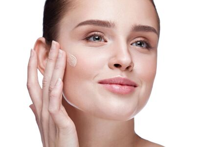 Beauty Face. Closeup Of Smiling Young Female Model With Smooth Soft Skin And Natural Facial Makeup. Portrait Of Beautiful Sexy Woman Putting Cream Foundation On Facial Skin. Cosmetics. High Resolutionの写真素材
