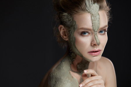 Spa Procedure. Closeup Of Beautiful Young Female Model Applying Cosmetic Mud Facial And Body Mask. Portrait Of Attractive Woman With Makeup And Clay Mask On Her Skin. Beauty Concept. High Resolutionの写真素材