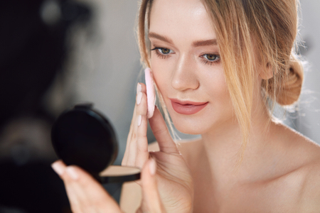 Closeup Of Sexy Female Applying Dry Powder Foundation Looking In Mirror.の写真素材