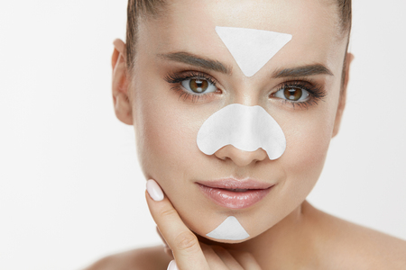 Beauty Cosmetics. Young Female With Cleansing Patches On Skin Touching Face. Closeup Of Attractive Girl With Fresh Natural Makeup And Facial Mask Strips On Nose, Chin And Forehead. High Resolutionの写真素材