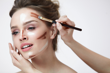 Woman Face Makeup. Closeup Of Hands Applying Contouring And Highlighting Lines On Female Facial Skin. Portrait Of Beautiful Girl With Natural Makeup Using Make-Up Contour Product. High Resolutionの写真素材