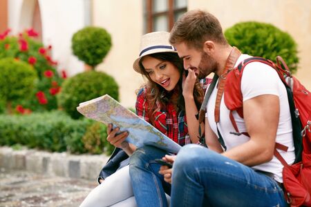 Young Tourist Couple Looking For Attractions On Map. Portrait Of Beautiful Smiling Girl In Hat And Happy Handsome Man  Reading Map Outdoors. High Resolution.の写真素材
