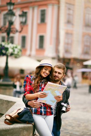 Couple Using Map Traveling On Vacations. Portrait Of Beautiful Happy Smiling People Standing On Street, Searching City Attractions On Map. Travel Concept. High Quality Image.の写真素材