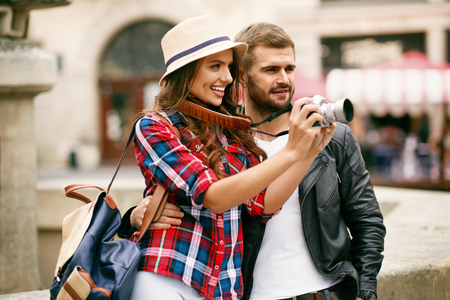 Beautiful Couple Taking Photos On Camera, Traveling. Portrait Of Happy Smiling People In Casual Stylish Clothes Making Photos Of  City Architecture. High Quality Image.の写真素材