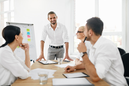 Business Team Meeting. Man Making Presentation In Office And Training Colleagues. Business People Sitting At Conference Table, Working On Project And Brainstorming Together. High Quality Image.の写真素材