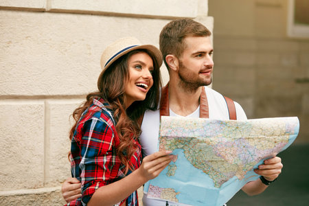 Happy Tourists. Beautiful Couple Sightseeing With Map. Smiling People In Stylish Clothes Walking...