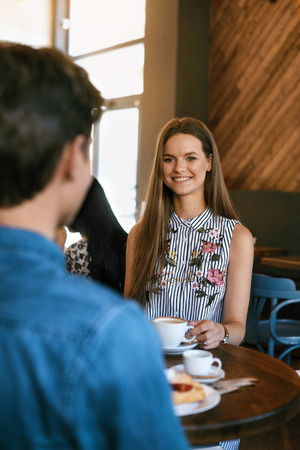 Couple With Coffee On Date. Beautiful Smiling People In Love Drinking Coffee And Talking In Cafe. Happy Young Man And Woman Enjoying Romantic Date With Croissant And Coffee In Bakery. High Qualityの写真素材