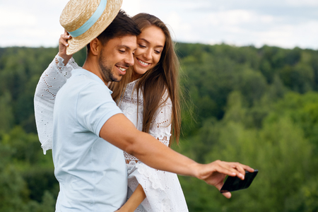 Romantic. Happy Couple In Love Taking Photos On Phone In Nature. Portrait Of Young Beautiful Woman And Handsome Man Making Selfie Photos On Vacation Outdoors. Relationships. High Quality Image.の写真素材