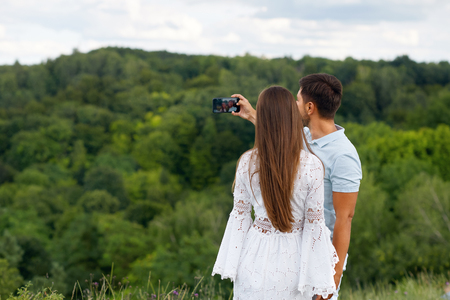 Romantic. Happy Couple In Love Taking Photos On Phone In Nature. Portrait Of Young Beautiful Woman And Handsome Man Making Selfie Photos On Vacation Outdoors. Relationships. High Quality Image.の写真素材