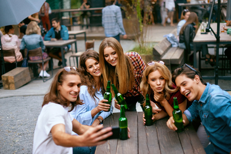 Group Of Friends Drinking Beer And Taking Photos On Phone. Happy Smiling Young People With Drinks In Hands Laughing And Spending Time Together On Summer Weekend. High Quality Image.の写真素材