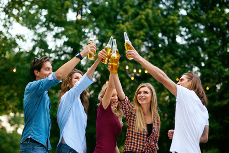 Friends Having Fun And Drinking Beer Outdoors. Beautiful Young Men And Women Cheering With Drinks, Enjoying Outdoor Party In Summer. People Celebrating. High Quality Image.の写真素材