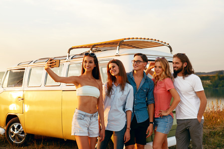 Friends Taking Photo On Phone In Nature In Summer. Happy Young Men And Beautiful Women Enjoying Summer Travel On Vacation, Spending Leisure Time Together Near Retro Bus Outdoors. High Resolution.の写真素材