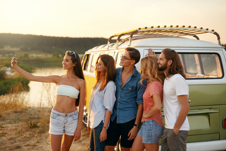 Friends Taking Photo On Phone In Nature In Summer. Happy Young Men And Beautiful Women Enjoying Summer Travel On Vacation, Spending Leisure Time Together Near Retro Bus Outdoors. High Resolution.の写真素材