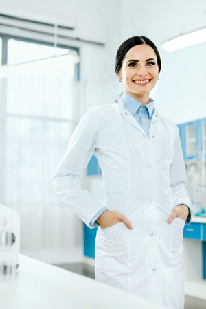 Scientist In Laboratory. Female Doctor At Work. Portrait Of Happy Young Beautiful Woman In White Laboratory Coat Near Workplace In Light Modern Laboratory. Medical Staff. High Qualityの写真素材