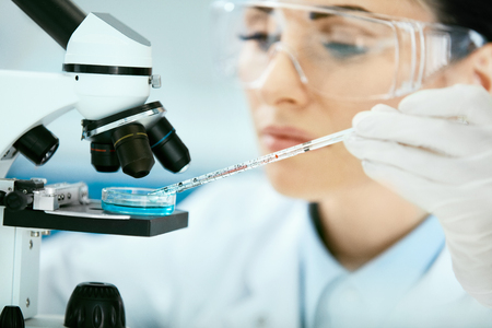 Medical Analysis. Female Scientist Doing Test In Laboratory. Close Up Of Young Woman Doctor In Medicine Glasses Using Microscope, Researching, Working In Light Modern Laboratory Clinic. High Qualityの写真素材