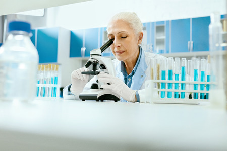 Laboratory Research. Woman Looking Through Microscope. Portrait Of Female Scientist In White Coat Working At Workplace In Modern Light Laboratory. Clinical Laboratory. High Quality Image.の写真素材