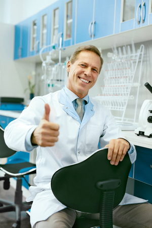 Happy Doctor At Work In Laboratory. Portrait Of  Professional Happy Smiling Mature Man In Lab Coat Showing Thumb Up In Light Workplace. Scientific Laboratory. High Resolution.の写真素材