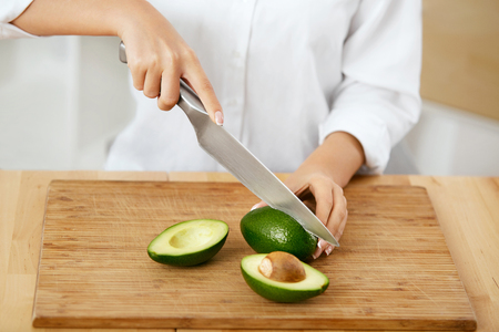 Diet. Female Hands Cutting Avocado In Kitchen.の写真素材