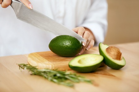 Diet. Female Hands Cutting Avocado In Kitchen.の写真素材