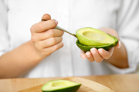 Eating Avocado. Woman Hands Peeling Fresh Avocado With Spoonの写真素材