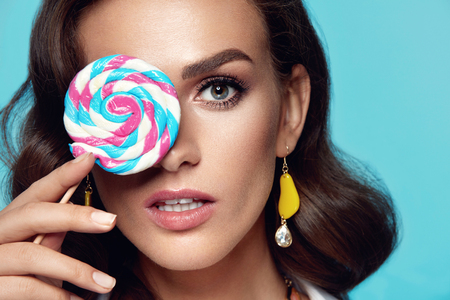 Beauty Makeup. Fashion Female Model With Candy. Beautiful Sexy Woman With Glamour Makeup Holding Lollipop In Hand. High Resolution.の写真素材