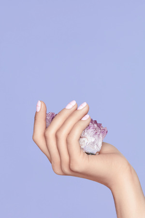 Manicure. Hand With Stylish Nails Holding Purple Gemstone. Close Up Of Female Fingers With Pastel Manicure Holding Violet Precious Stone On Violet Background. High Quality Image.の写真素材