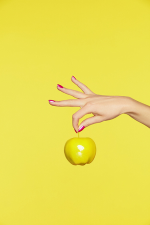 Nails Design. Female Hands With Colorful Nails Holding Apple On Yellow Background. Close Up Of Woman Fingers With Fashion Purple Manicure Holding Yellow Apple. High Quality Image.