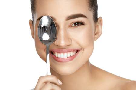 Eye Skin Care. Beautiful Woman With Healthy Skin Holding Cold Spoon Near Eye On White Background. High Resolution.の写真素材
