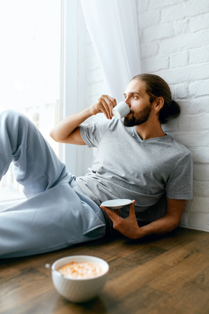 Morning Coffee. Man Enjoying Hot Drink And Eating Breakfast While Sitting Near Window At Home. High Resolution.の写真素材