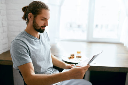 Man Reading Newspaper While Having Breakfast At Home In Morning. High Resolution.
