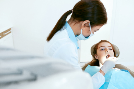 Stomatology. Dentist In Medicine Mask Working With Girl Teeth, Kid Sitting In Dental Clinic. High Resolution.の写真素材