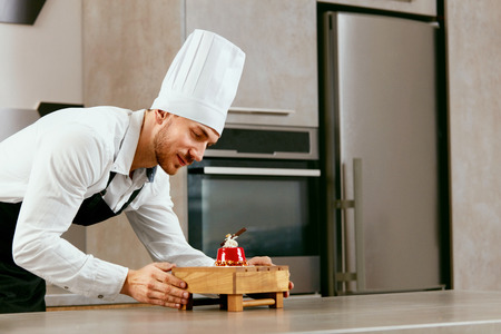 Handsome Pastry Chef Working With Sweet Dessert On Table In Kitchen. High Resolution.の写真素材