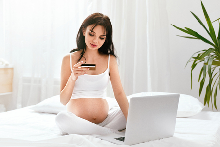 Online Shopping. Pregnant Woman Shopping In Internet. Beautiful Female With Computer And Credit Card At Home. High Resolutionの写真素材