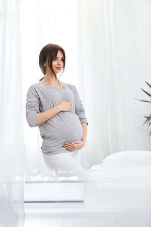 Pregnant Girl. Beautiful Smiling Pregnant Woman With Baby Belly At Home. High Resolutionの写真素材