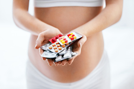 Pregnancy Vitamins And Medications. Close Up Of Pregnant Woman Holding Pills In Hand Near Belly. High Resolutionの写真素材