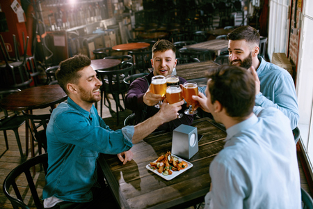 Men Drinking Beer In Pub. Friends Toasting With Alcohol Drinks in Bar. High Resolution.の写真素材